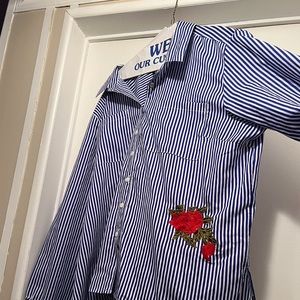 Button up shirt with embroidered rose. Bottom of sleeves tie into a bow.